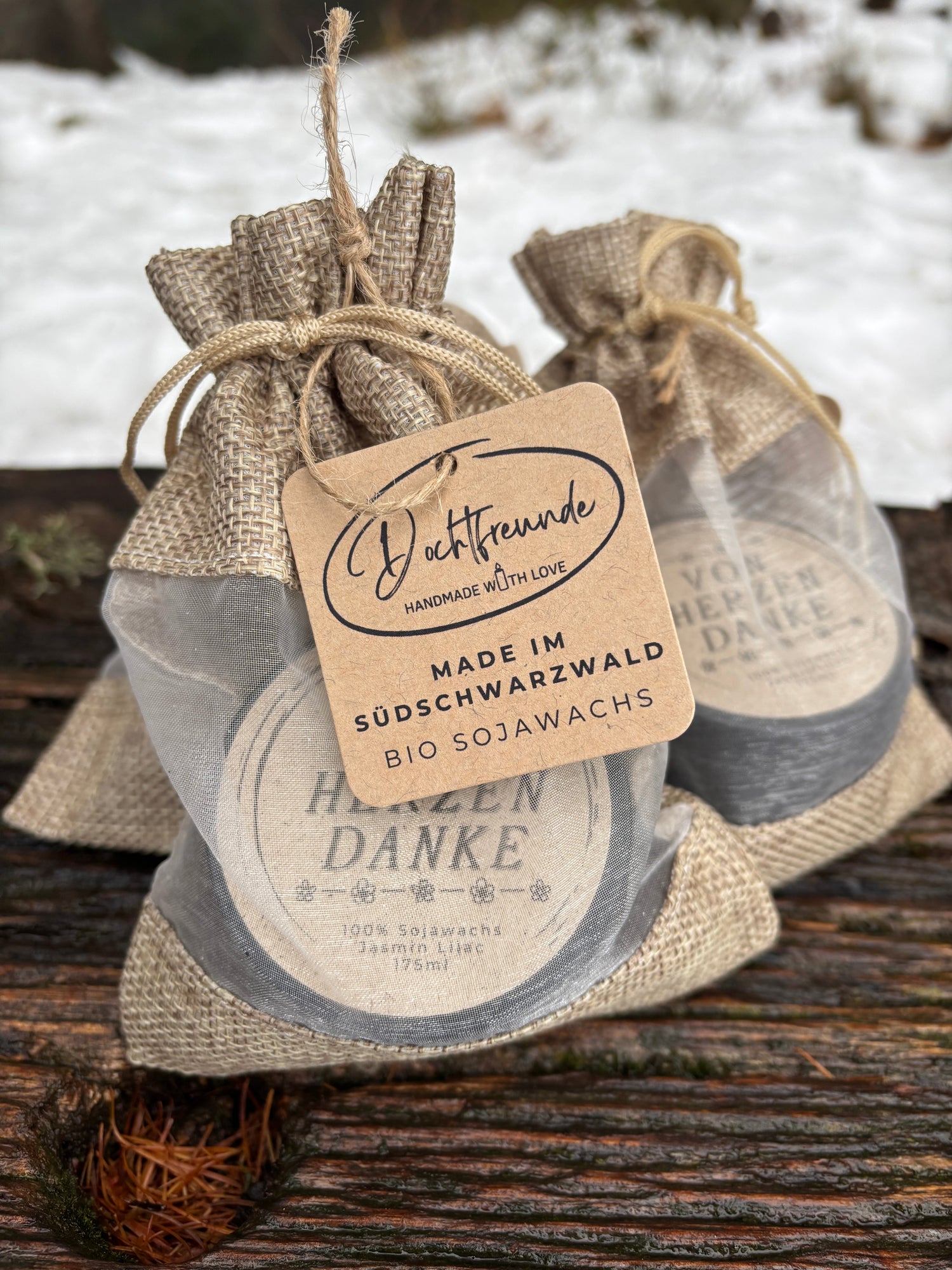 Handgemachte Mini-Duftkerzen in schwarzen Dosen mit getrockneten Blüten und lustigem Aufkleber 'Der hat Gleitzeit' – ideal als Wichtelgeschenk aus Sojawachs.