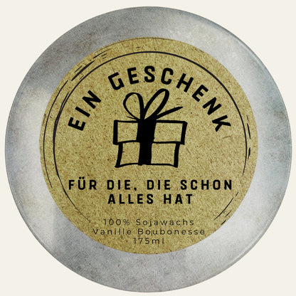 Dosendeckel mit Kraftpapier-Etikett, Geschenk-Symbol und Spruch „Ein Geschenk für die, die schon alles hat“